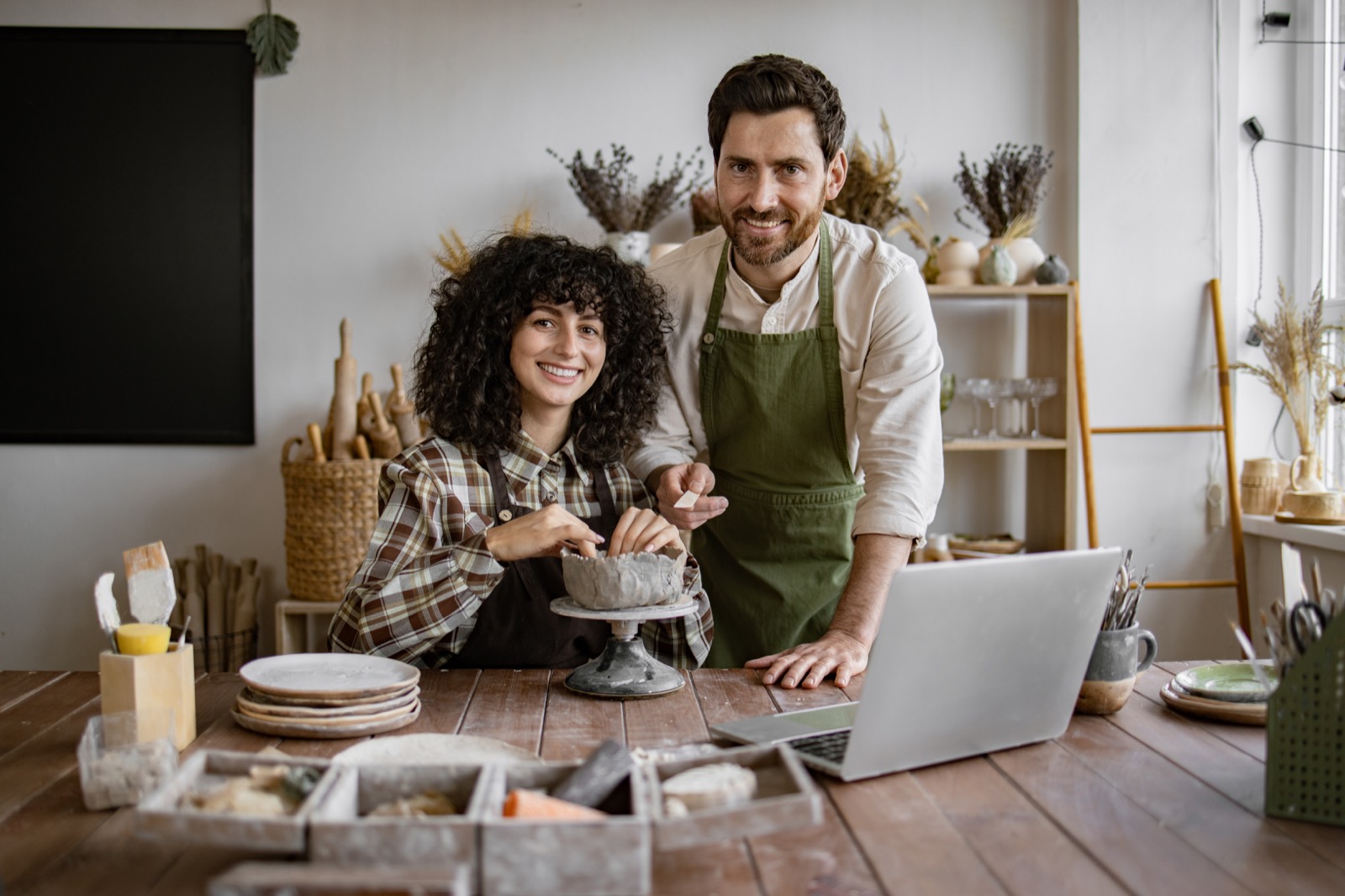 A small business owner smiling at her desk with her team working behind her